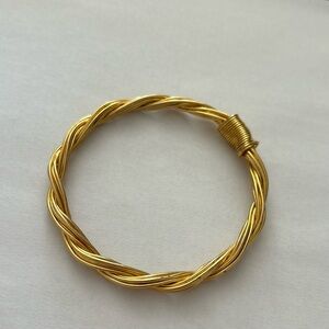 Twisted gold tone bangle bracelet wire strand is twisted with a wrap design